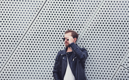 handsome man with beard in autumn leather jacket standing outdoorsの写真素材