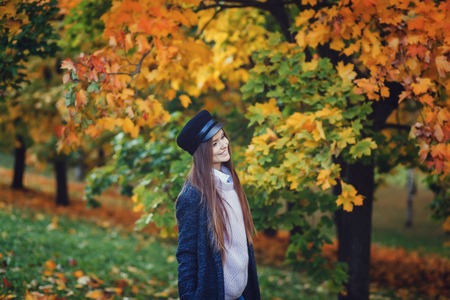 young beautiful woman in a hat walks in autumn parkの写真素材
