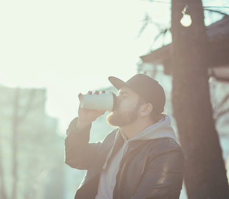 stylish man in a leather jacket drinking coffee in an urban environment