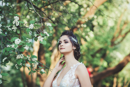 portrait of a beautiful bride in a wedding dress near a flower treeの写真素材