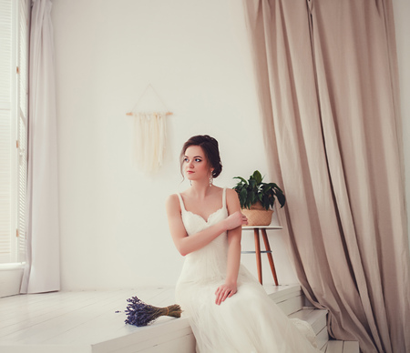 beautiful portrait of the bride in a wedding dress sitting in the roomの写真素材