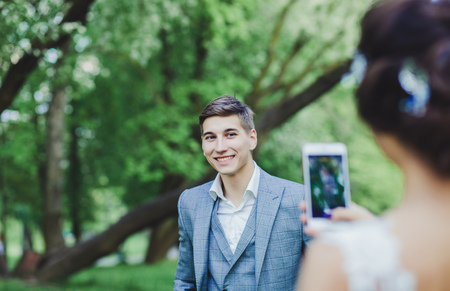 the bride takes pictures of the groom on his phone on the wedding dayの写真素材