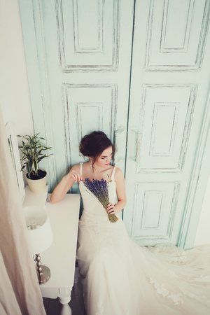 Luxury bride model sitting on chair with bouquet like at home in studio room.の写真素材