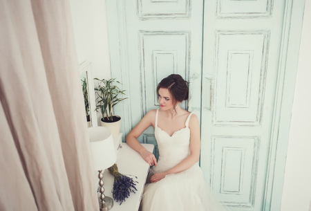 portrait of a beautiful bride in a wedding dress sitting at the table. waiting for the groomの写真素材
