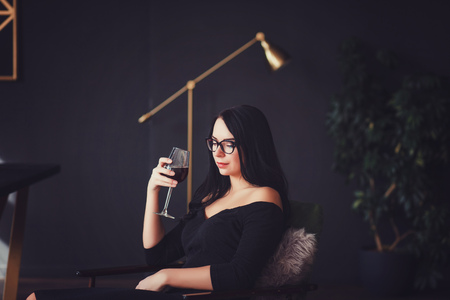 Young celebrating woman black dress. Beautiful model portrait  hold wine glass.の写真素材
