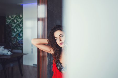 beautiful young woman with curly hair wearing red dressの写真素材
