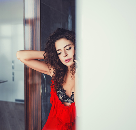 beautiful elegant woman in red dress with curly hairの写真素材