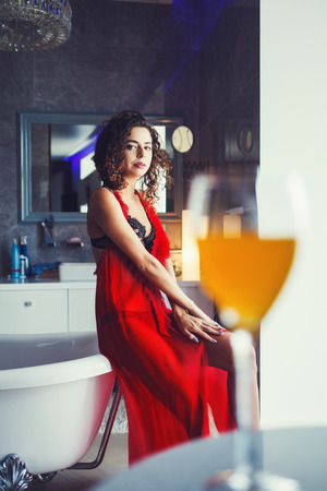 luxurious and rich lady in a red dress sitting on the bathの写真素材