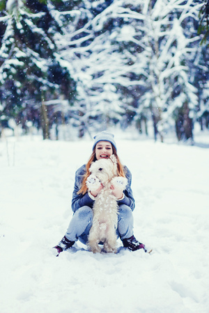 Little dog with owner spend a day at the winter forest playing and having funの写真素材