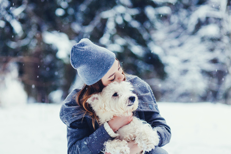 Young dog owner girl plays with white terrier in park outdoor.の写真素材
