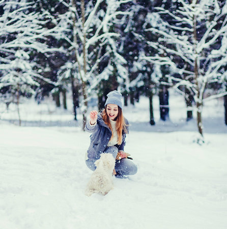 Happy beautiful young woman playing in a winter day. Friendship, pet and humanの写真素材