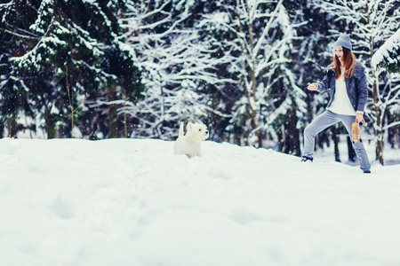 Woman walking with white terrier dog in winter forestの写真素材