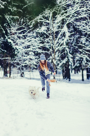 happy woman running with dog in winter forestの写真素材