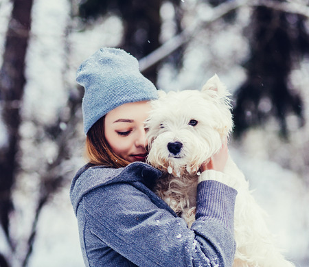 portrait of young beautiful woman hugging white terrier dog.の写真素材