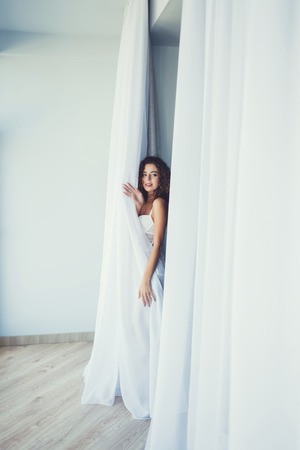 beauty curly lady in lingerie posing near curtainsの写真素材
