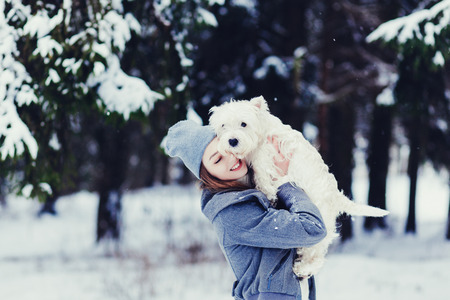 Happy beautiful young woman hugging dog in a winter dayの写真素材
