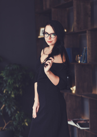 successful lady in black dress posing in officeの写真素材