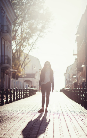 woman in sunglasses and a leather jacket walks around the European cityの写真素材