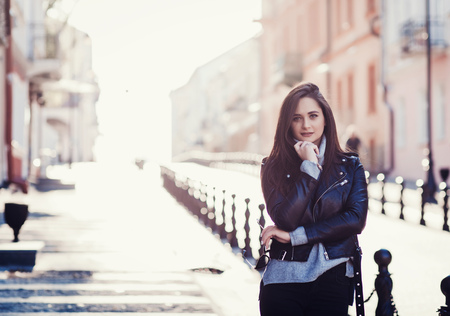 Happy young beautiful woman in city street stylish fashion model wearing black leather jacketの写真素材