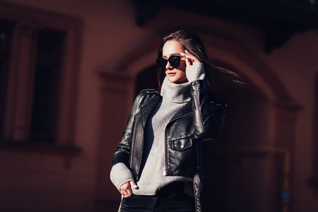 Young fashion brunette woman in leather jacket posing in cityscapeの写真素材