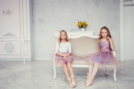 Little girl sitting in ballet studio with copy space. Two cute small ballerinas sitting on classical dance schoolの写真素材