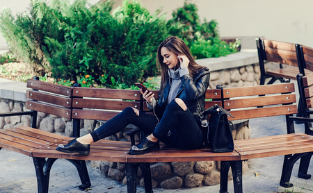Beautiful stylish young woman listening to music while resting in parkの写真素材