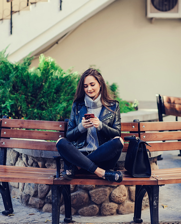 young beautiful woman in leather jacket listening to music on the phoneの写真素材