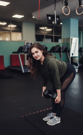 Sporty woman does the exercises with dumbbells in gym. Strength and motivation.の写真素材