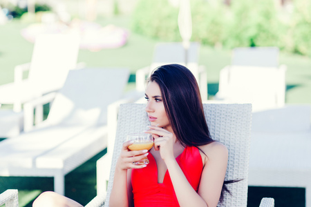 attractive brunette woman drinking juice and and relaxing on chairの写真素材