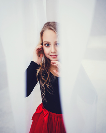 Portrait of happy pretty curly little girl standing on studio or roomの写真素材