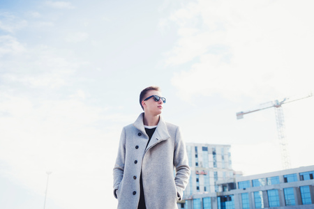 Handsome cool young man in coat with sunglassesの写真素材