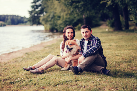 Happy smiling couple resting at the park with a dog.の写真素材
