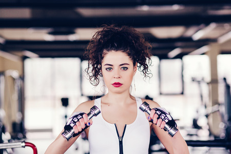 Athletic young woman with dumbbells in gymの写真素材
