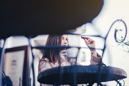 a young woman in a cafe drinking coffee with cookiesの写真素材