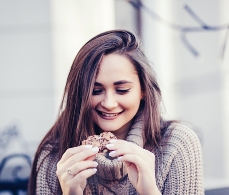 happy young woman eating cookie in cafeの写真素材