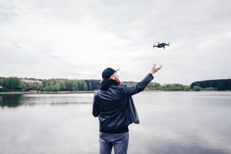 Man operating / flying with drone by the river. Back view shot の写真素材