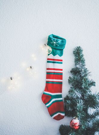 Christmas sock hanging on the wall next to the spruceの写真素材
