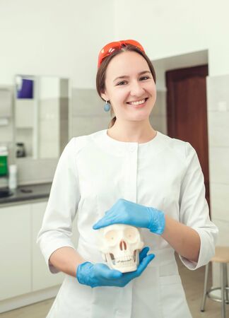 woman doctor smiling holding skull in handの写真素材