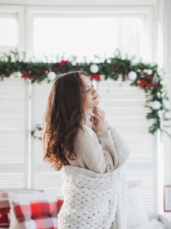 beautiful woman in warm knitted clothes at home. festive atmosphere of the new yearの写真素材