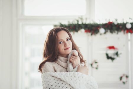 girl indoor portrait. Young beautiful woman in warm knitted clothes at homeの写真素材