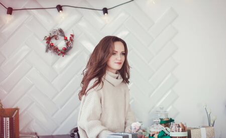 a beautiful young woman in a warm wool sweater sits in the kitchen waiting for Christmasの写真素材
