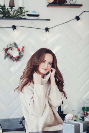 a beautiful woman with a hairstyle poses in a cozy decorated christmas apartmentの写真素材