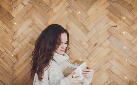 a woman in a sweater holds a Christmas gift boxの写真素材