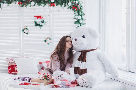 Portrait of pretty woman embraced teddy bear in christmas roomの写真素材
