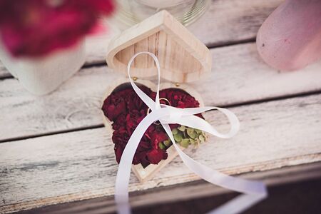 Wedding rings with red flowers on wooden surface. Wedding card, Valentine's day greetings.の写真素材
