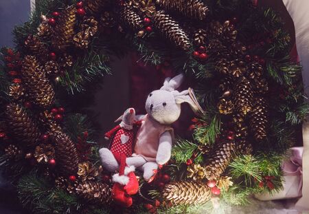 Christmas decorated showcase. toy rabbit and mouse on the background of spruce and pine conesの写真素材