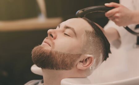 barber washing bearded man head in barbershopの写真素材