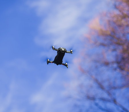 compact black drone flying in blue sky