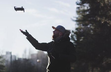 young man holds a drone after a flight.