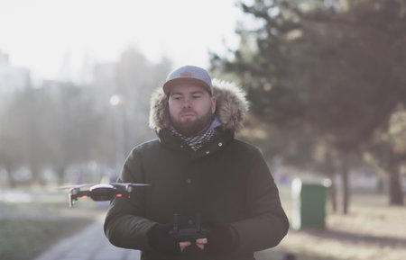 hipster bearded man in cap with flying drone outdoors